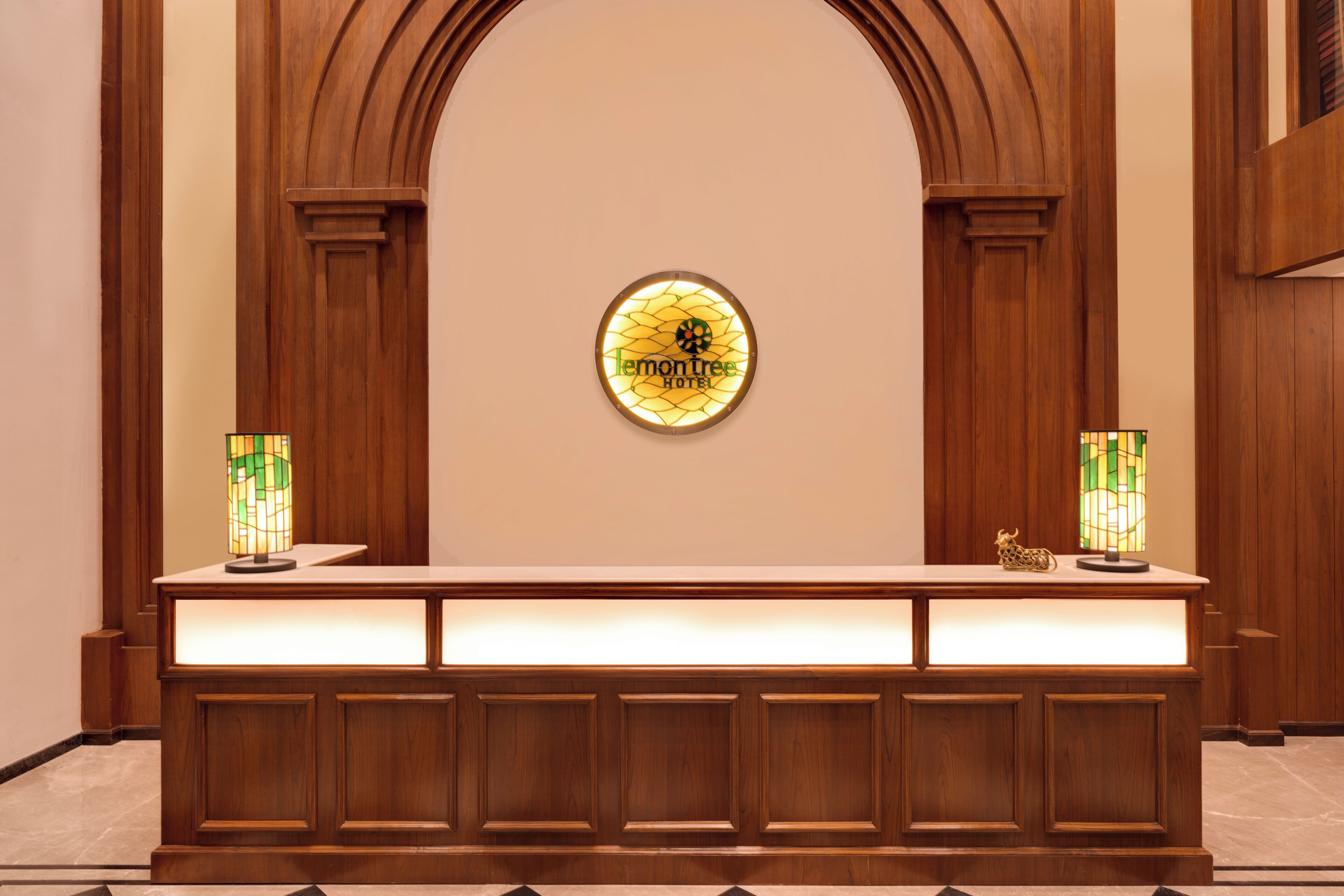 Una mesa de recepción con un cartel que dice "Lemon Tree Hotel" y dos lámparas de vitral.
