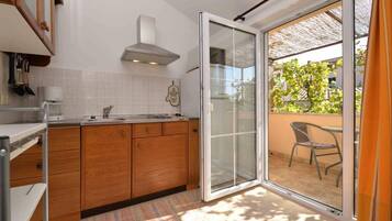 A kitchen with wooden cabinets, a white countertop, and a built-in oven. There is a sliding glass door leading to an outdoor patio with a table and chairs.