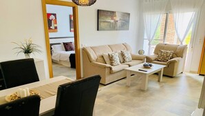 A modern living room with a beige sofa, a coffee table, and a dining area with a table and chairs.