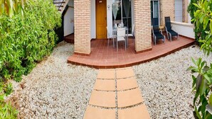 A courtyard with a gravel path leading to a seating area with chairs and a table.