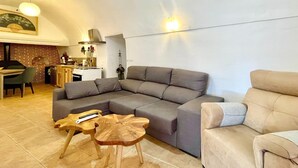A modern living room with a grey sectional sofa, a wooden coffee table, and a beige armchair. - Cave House in Cúllar near Tabernas Desert (Cúllar)