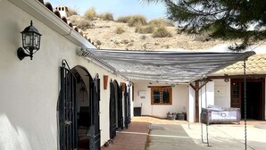 A building with a covered patio, black metal gates, and a covered outdoor seating area. - Cave House in Cúllar near Tabernas Desert (Cúllar)