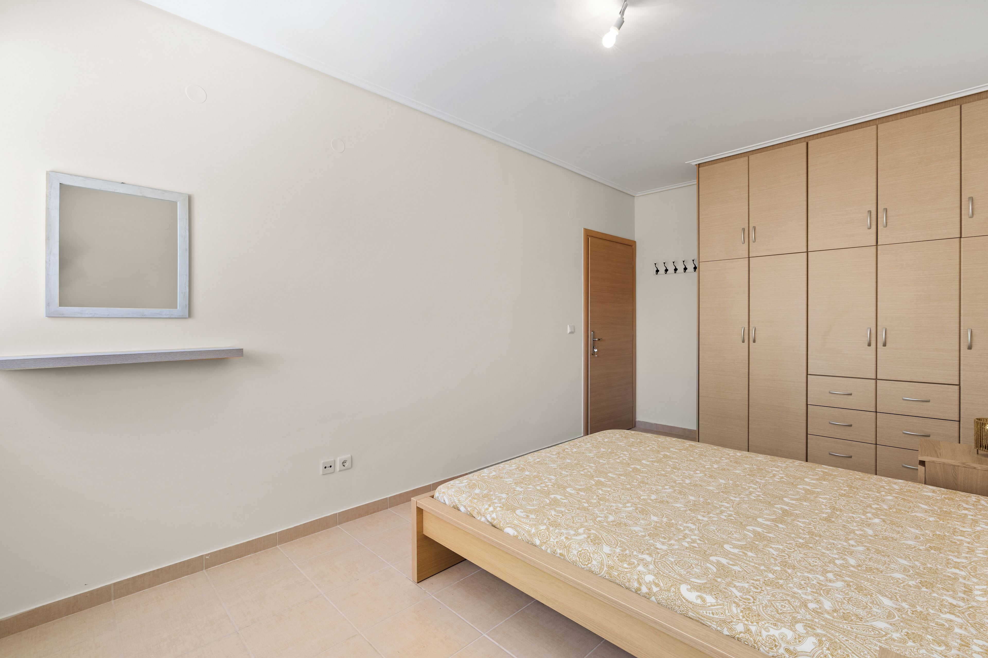 Quarto com cama, guarda-roupa e uma pequena prateleira.