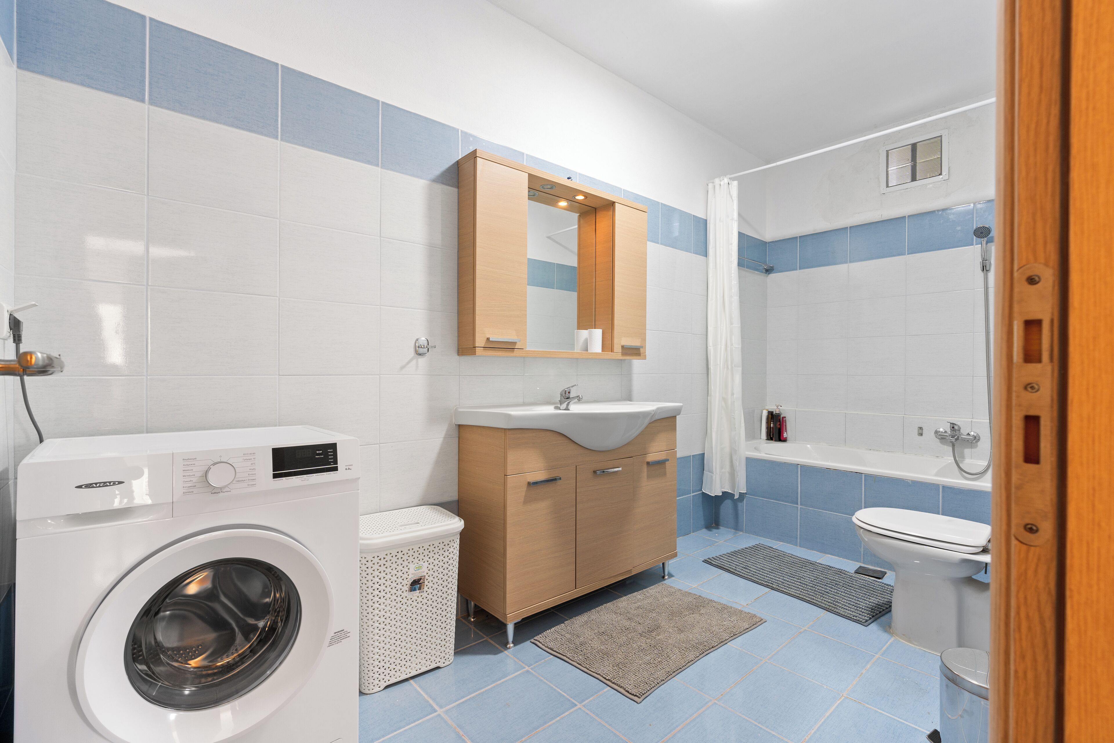 Un baño pequeño con lavadora, lavamanos y ducha.