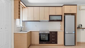 Eine moderne Küche mit hellen Holzschränken, einem Einbauofen, einer Mikrowelle und einem Kühlschrank.