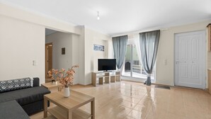 Ein modernes Wohnzimmer mit einer Couch, einem Couchtisch, einem Fernseher auf einem Schrank und einer Glastür, die zu einem Außenbereich führt.