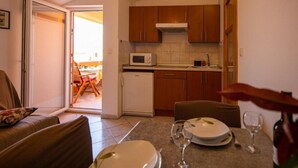 A compact kitchen with wooden cabinets, a microwave, and a dining area with a table set for two.