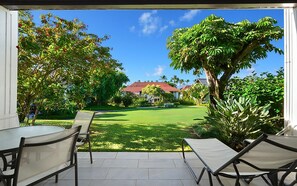 Terassi, jossa on pöytä ja tuoleja, nurmikko ja taustalla näkyvä talo.
