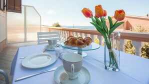 A table set for a meal with croissants, a cup, and tulips on a balcony overlooking a scenic view. - Beautiful apartment near Rtić beach (Primošten)