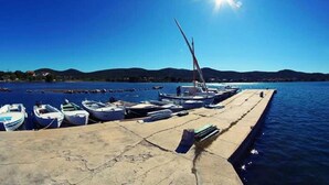 Eine Marina mit mehreren kleinen Booten an einem Betonsteg, und ein klarer, blauer Himmel mit Sonnenschein.