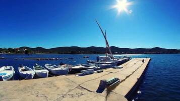 Eine Marina mit mehreren kleinen Booten an einem Betonsteg, und ein klarer, blauer Himmel mit Sonnenschein.