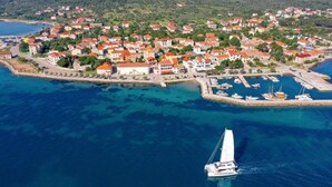Luftaufnahme einer Küstenstadt mit Häusern, einem Yachthafen und einem Segelboot.