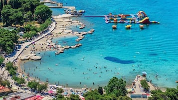 Una spiaggia costiera con acque cristalline, numerose imbarcazioni e un parco acquatico.