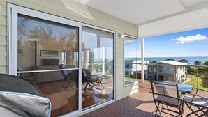 Un balcon avec vue sur la mer et les bâtiments, une table avec des chaises et un canapé.