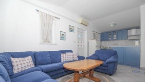 A living room with a blue sofa set, a wooden coffee table, and a patterned cushion. - Apartment in Tribunj near Tribunj Beach (Tribunj)