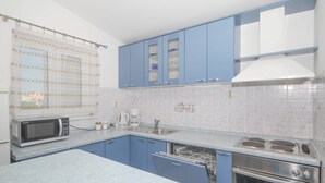A kitchen with blue cabinets, a microwave, a stove, and a dishwasher. - Apartment in Tribunj near Tribunj Beach (Tribunj)