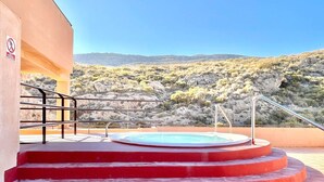 Zona de piscina en la azotea con escalones rojos que conducen a un jacuzzi, rodeada por un paisaje desértico.