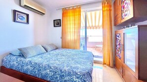 Un dormitorio con cama, aire acondicionado y vistas al exterior.