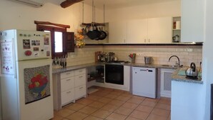 A compact kitchen with white cabinets, a built-in dishwasher, and a hanging pot rack. - Holiday Home in Orgiva with Mountain Views (Orgiva)