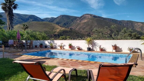 A swimming pool with lounge chairs, surrounded by potted plants and a view of mountains. - Holiday Home in Orgiva with Mountain Views (Orgiva)