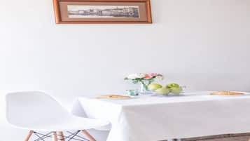 A dining table with a white tablecloth, a vase with flowers, and a plate of food.