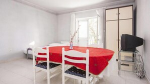 A room with a dining table, chairs, a TV on a stand, and a sliding door. - Apartment in Šibenik near Adriatic Beaches (Šibenik-Brodarica)