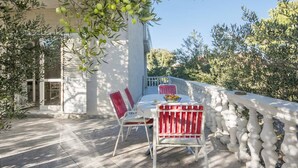 An outdoor dining area with a table and chairs, a white railing, and olive trees in the background. - Apartment in Šibenik near Adriatic Beaches (Šibenik-Brodarica)