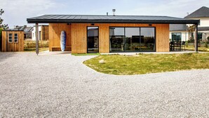 En moderne bygning med træfacade, store vinduer og en grusvej.