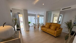 A modern living room with a yellow sofa, a dining area with a glass table, and a kitchen area with a white sink. - Ground floor  La Zenia beach, Orihuela Costa (La Zenia)