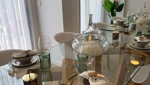 A modern dining area with a glass table set for a meal, featuring clear glassware, a decorative centerpiece, and elegant tableware. - Ground floor  La Zenia beach, Orihuela Costa (La Zenia)