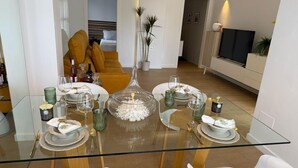 A modern dining area with a glass table, white chairs, and a sofa in the background. - Ground floor  La Zenia beach, Orihuela Costa (La Zenia)