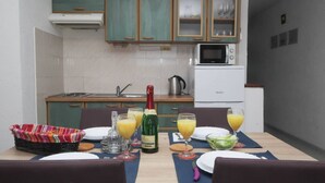 Een eettafel gedekt met borden, glazen, een fles champagne en een saladekom.