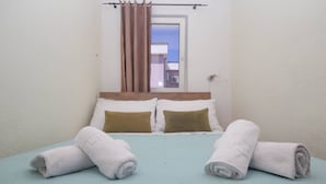 Een hotelkamer met een bed, kussens en handdoeken.