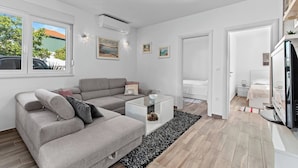 Un salon moderne avec un canapé gris, une table basse en verre et un tapis noir et blanc.