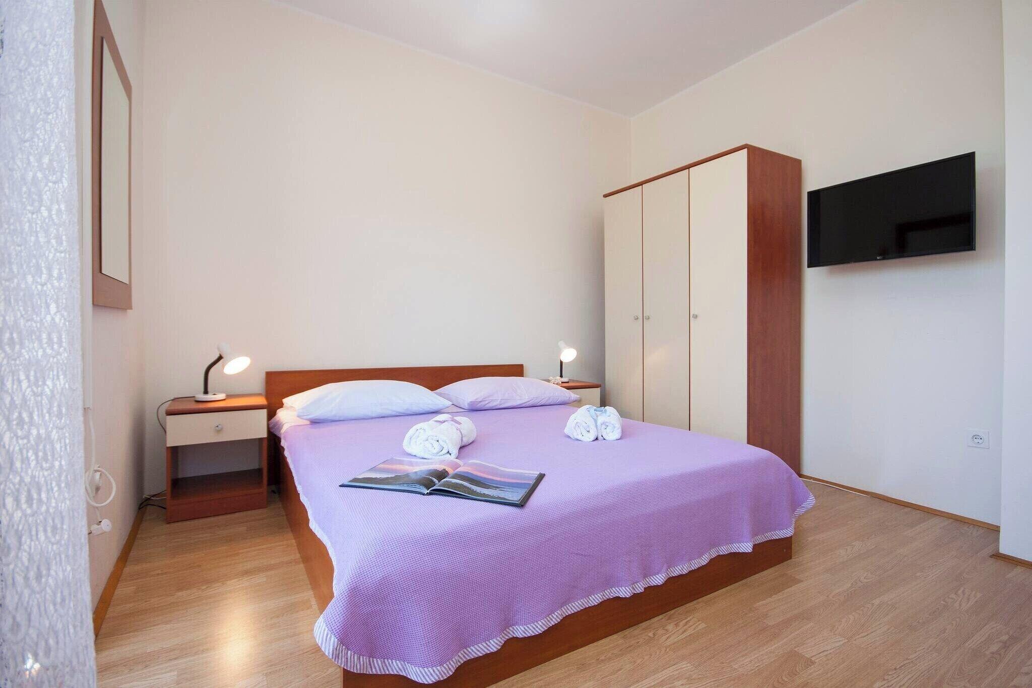 Un dormitorio con una cama, mesitas de noche, un armario y un televisor.