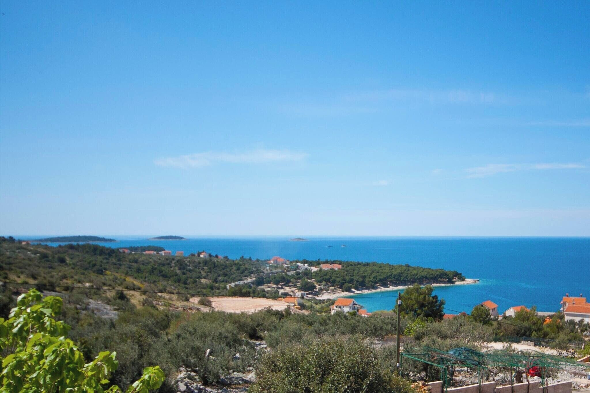 A coastal landscape with buildings, a clear sky, and the sea.