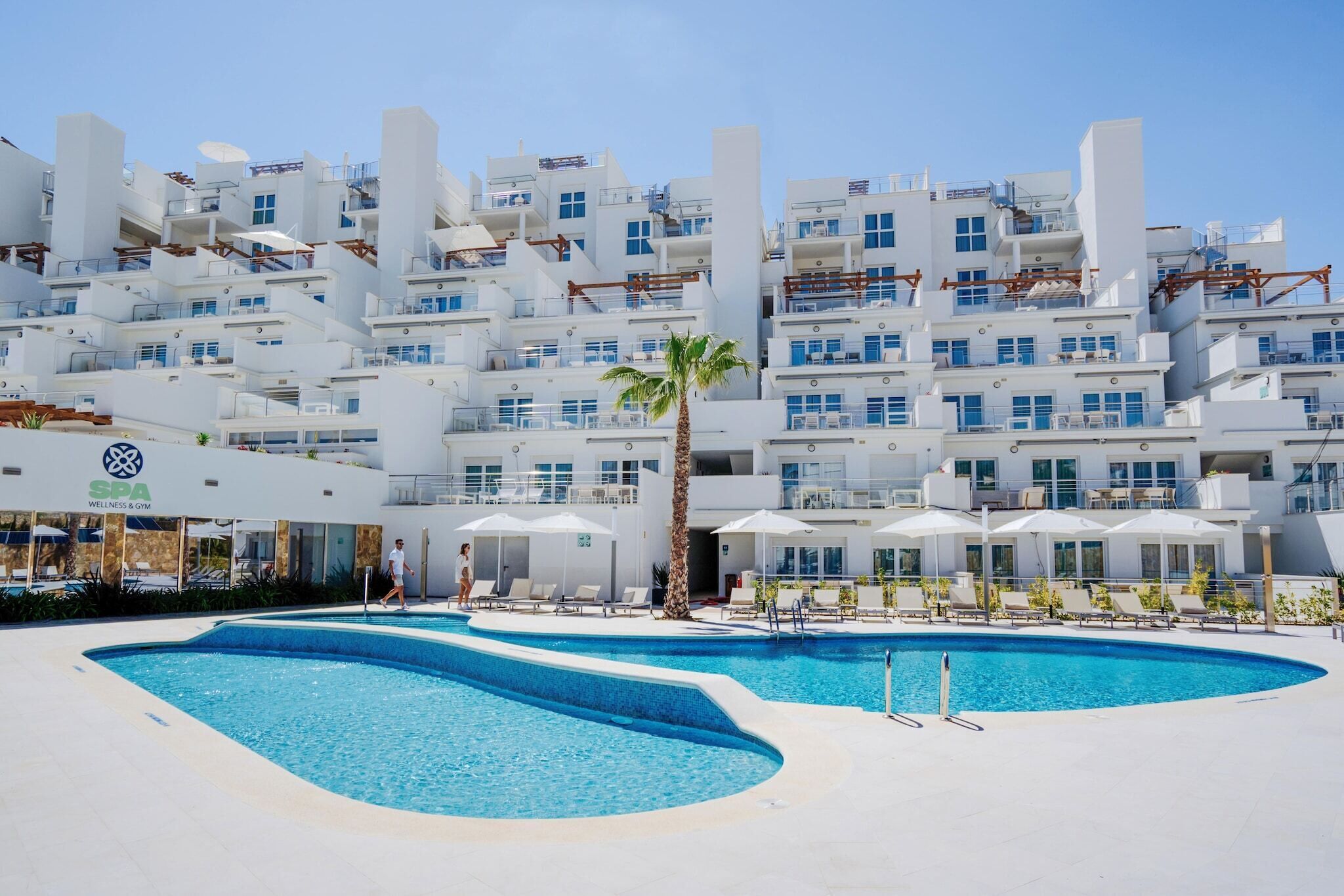 Un hotel moderno con zona de piscina, varios balcones y un centro de bienestar.