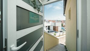 Une vue depuis un balcon, avec une enseigne indiquant « Boutique de jardin », et un aperçu des bâtiments environnants et des voitures garées.