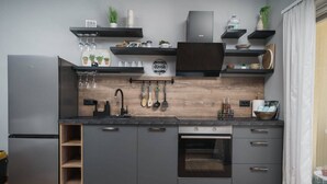 Une cuisine moderne avec des meubles de couleur grise, un four encastré et un pare-feu en bois.