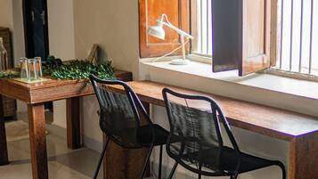 Un comedor con una mesa de madera, dos sillas negras, un banco acolchado azul y un tapiz estampado.