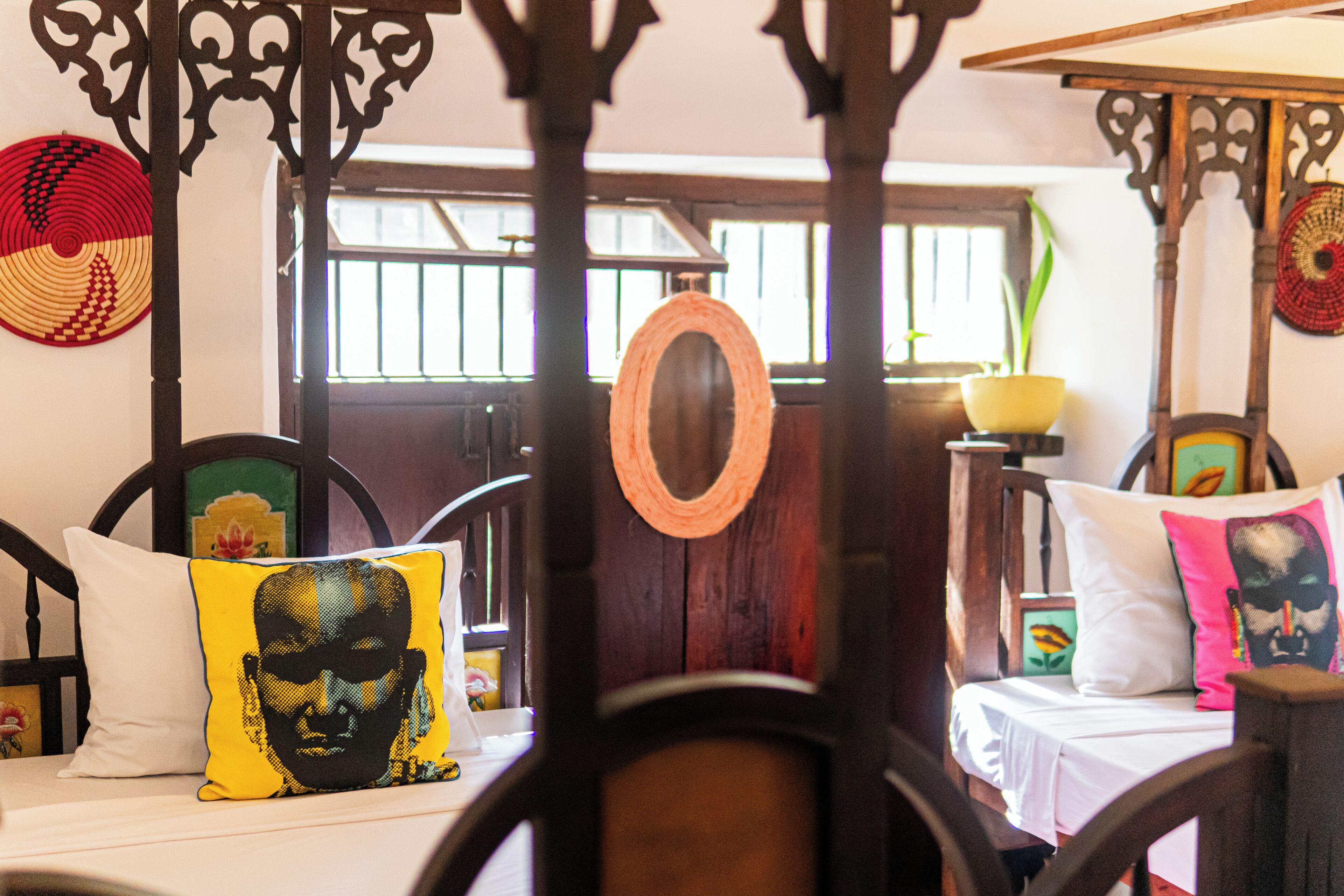 Ein traditionell eingerichtetes Zimmer mit einem hölzernen Bettgestell, einem runden Spiegel und dekorativen Wandteppichen.