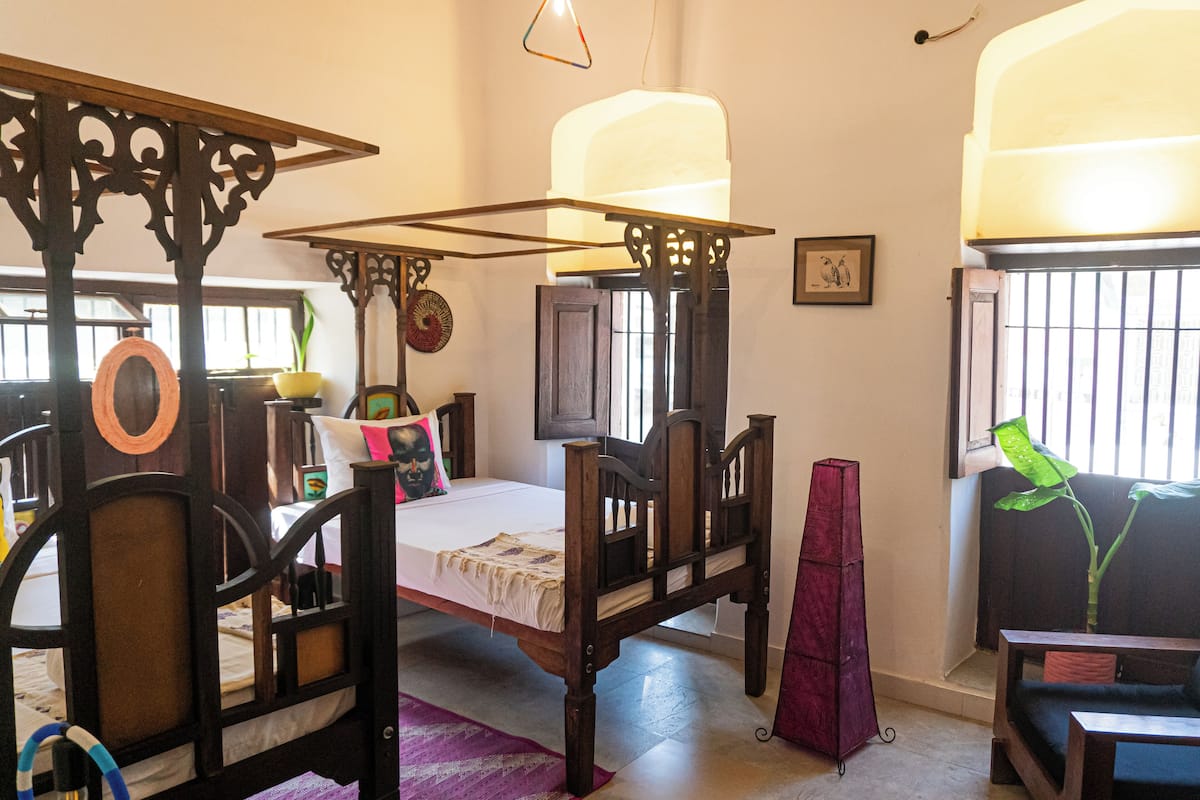 A traditional room with a four-poster bed, a television, and a window with bars.