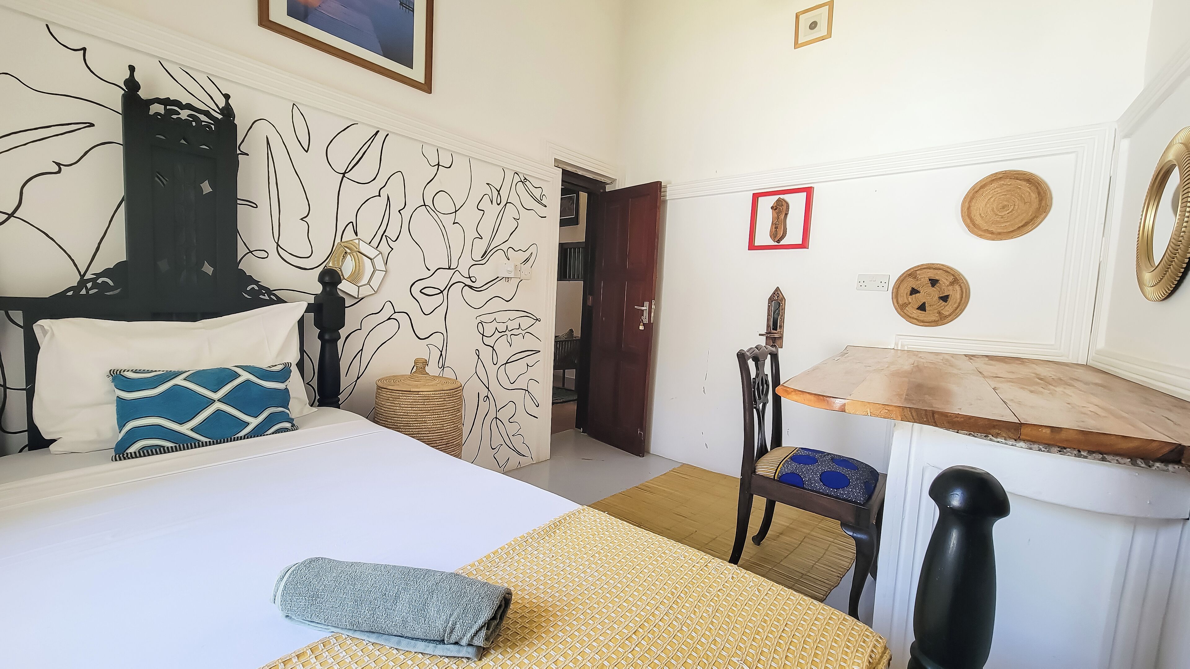 A bedroom with a bed, a wooden table, a chair, and a decorative wall.