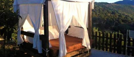 A single-room tent with a bed, surrounded by a wooden deck and a wooden fence.