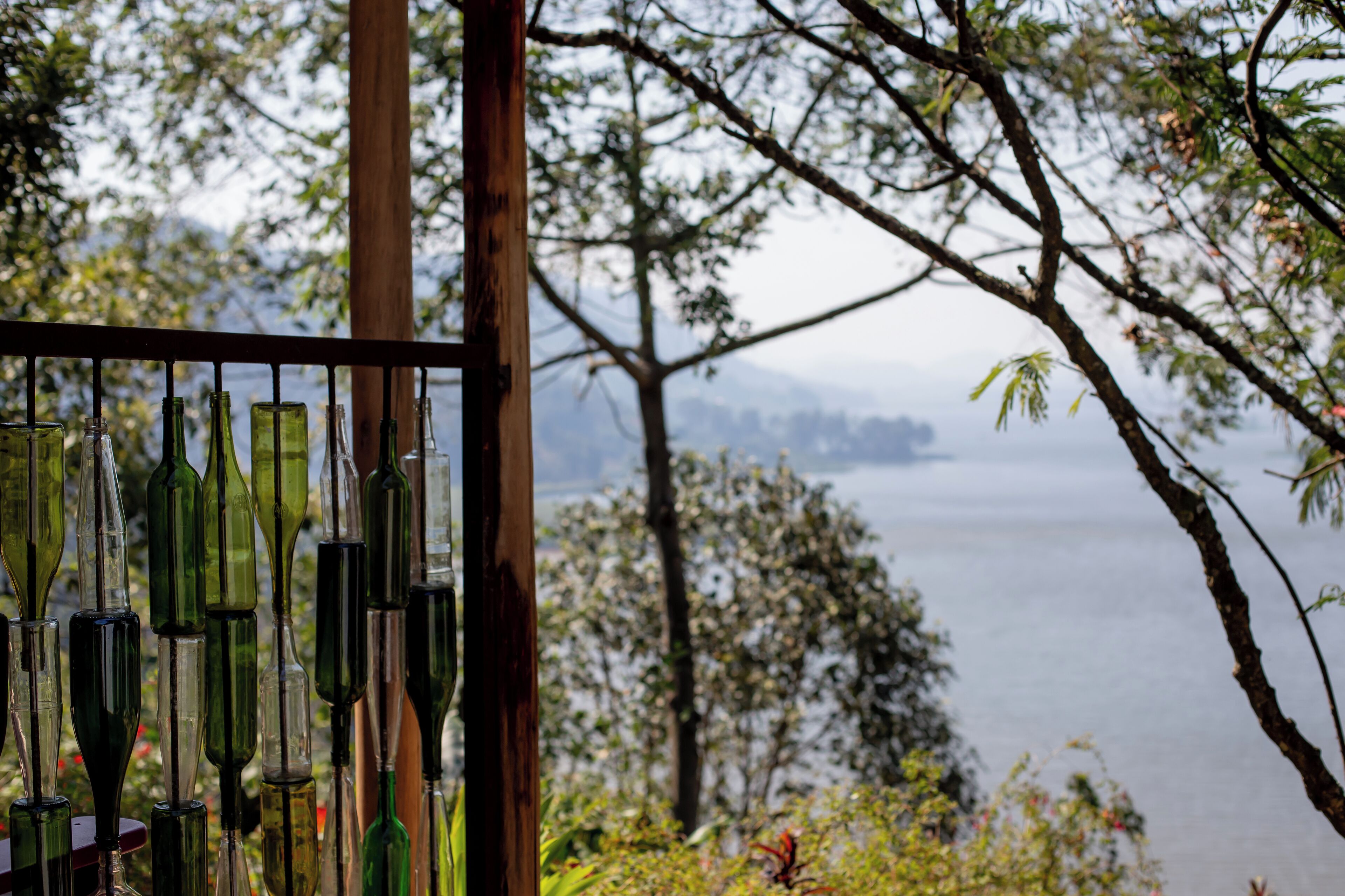 A view of a lake with a wooden structure and glass bottles in the foreground.