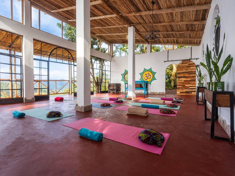 A spacious yoga studio with large windows, wooden beams, and a view of the outdoors.