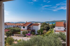 Un quartiere residenziale con case dai tetti rossi, immerso nel verde e con vista sul mare e sulle colline in lontananza.