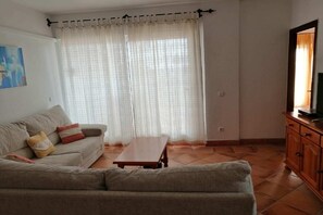 Ein Wohnzimmer mit einer Couch, einem Couchtisch und einem Fernseher auf einem Holzschrank.