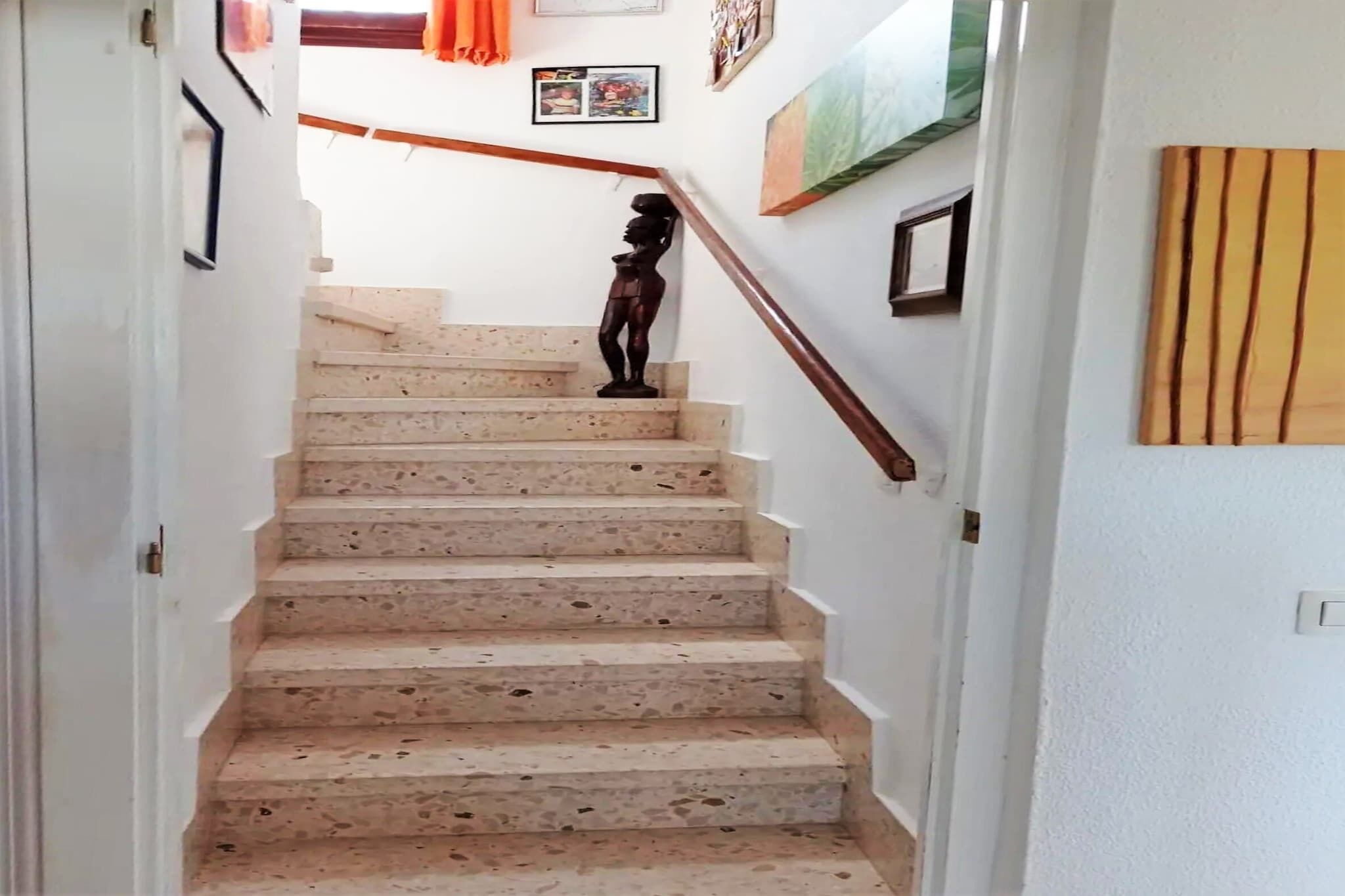 Una escala amb barana, una paret amb un quadre i una porta.