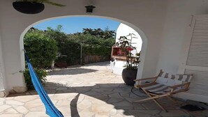 Un patio al aire libre con una hamaca, una silla de madera y plantas en macetas.